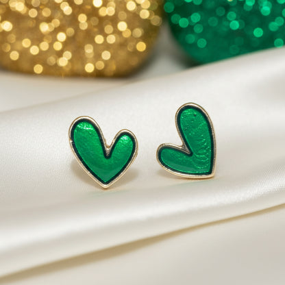 Evergreen Heart Earrings on a white surface with gold and green blurred background