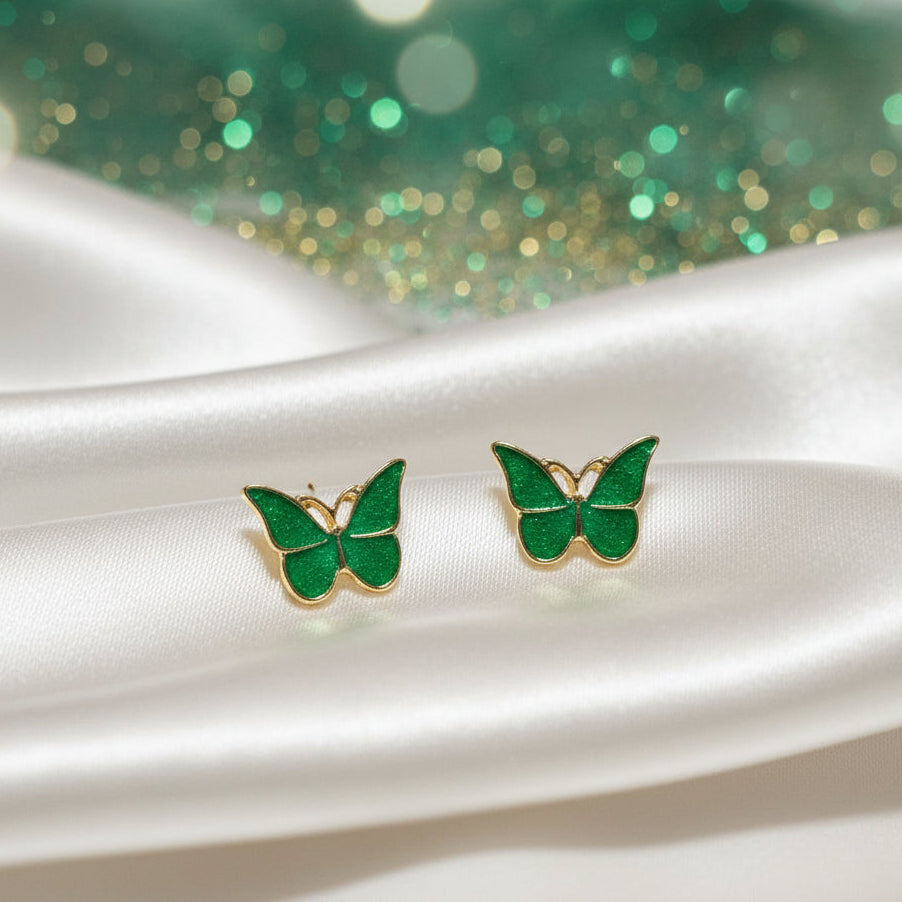 Garden Green Butterfly Earrings on white fabric with a green glittery background