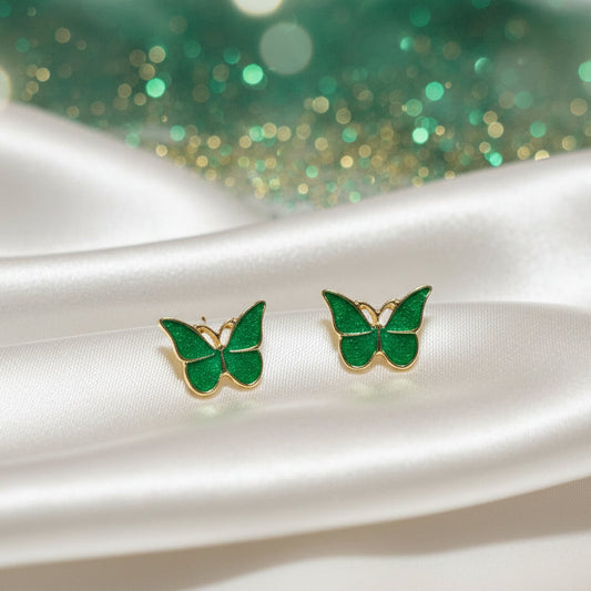 Garden Green Butterfly Earrings on white fabric with a green glittery background