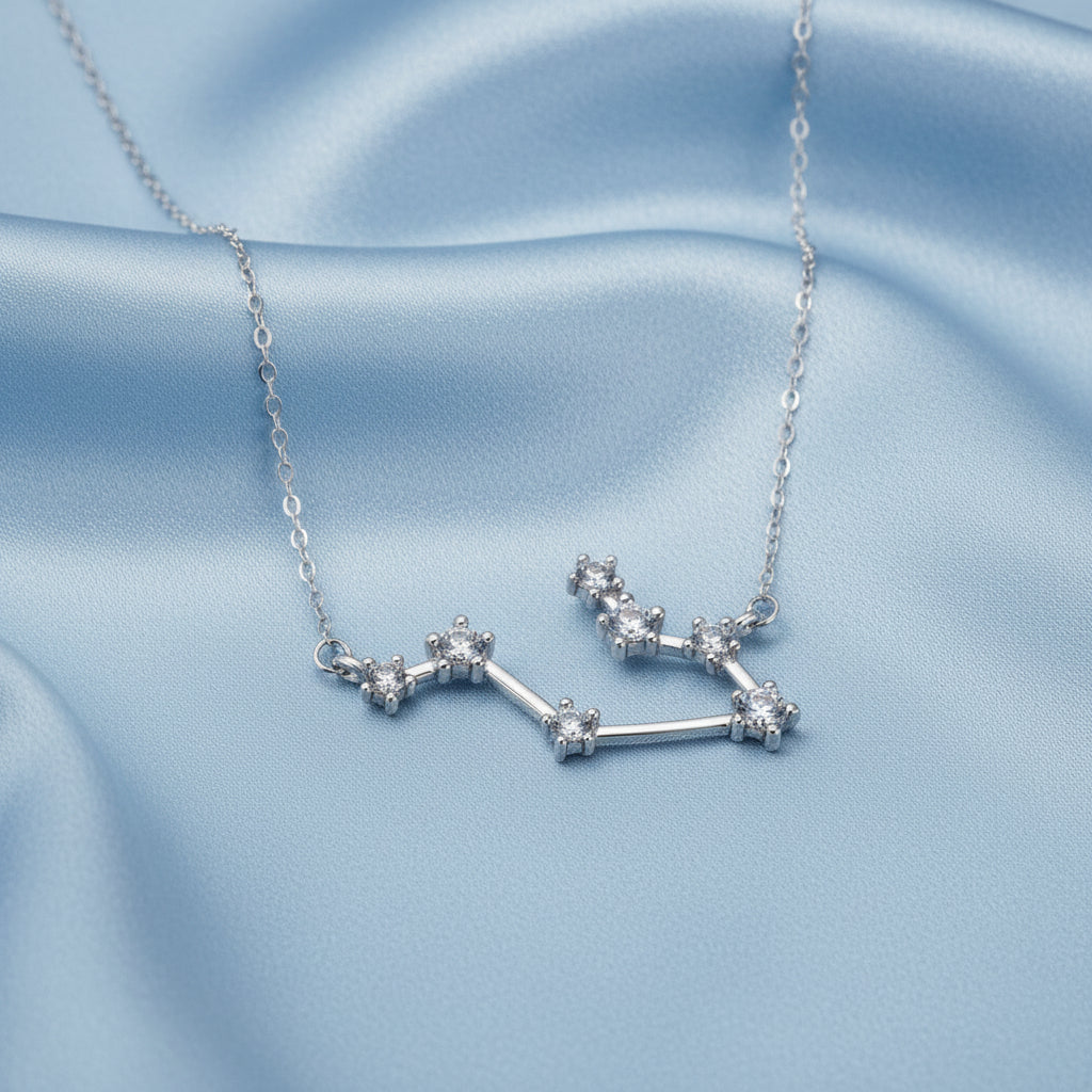 Gemini Necklace on a light blue satin background