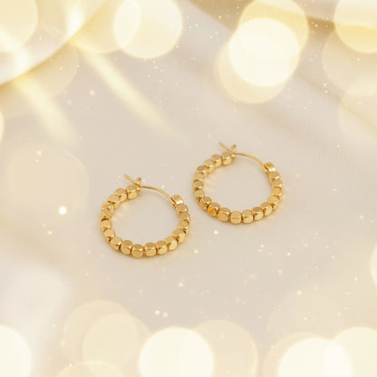 Gold Bead Accent Hoop Earrings on a beige fabric background
