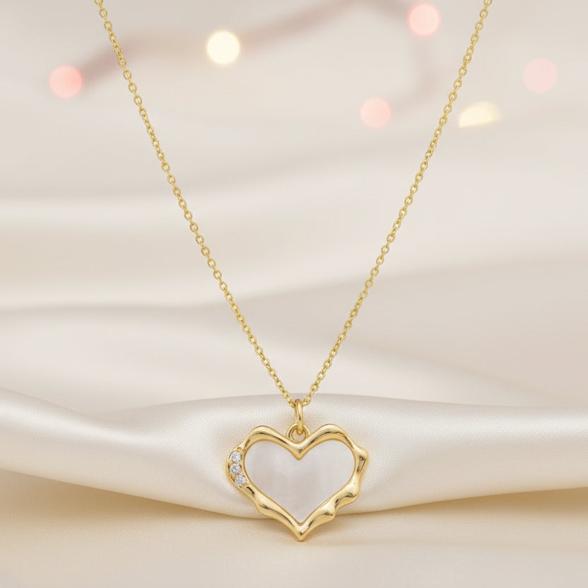 Gold Heart Mother of Pearl Necklace on a soft fabric background with blurred lights