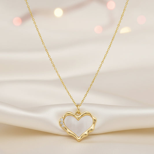 Gold Heart Mother of Pearl Necklace on a soft fabric background with blurred lights