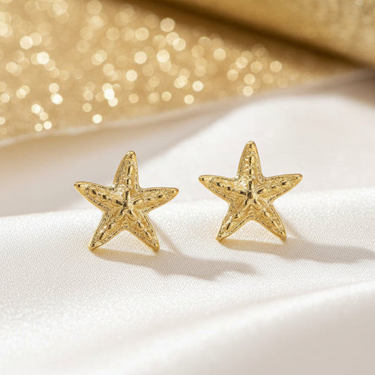 Gold Starfish Earrings on a white surface with a glittery gold background