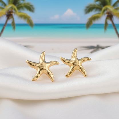 Gold Tide Starfish Earrings on a white fabric on a beach