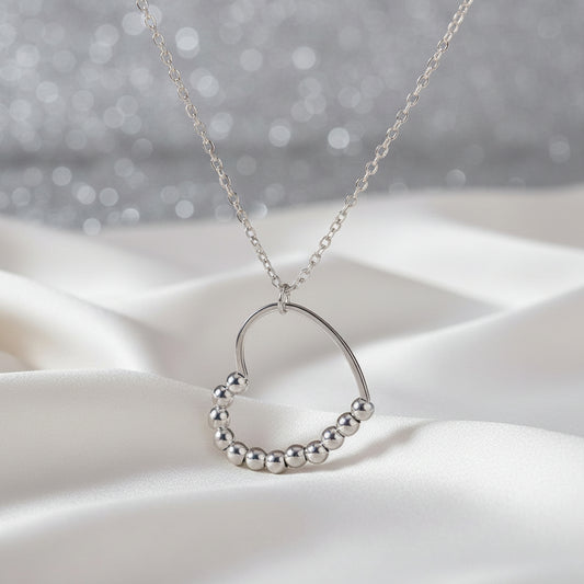 Silver Heart Spinner Necklace on a white fabric background