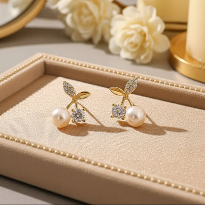Pair of gold earrings with pearls and gemstones on a light fabric background