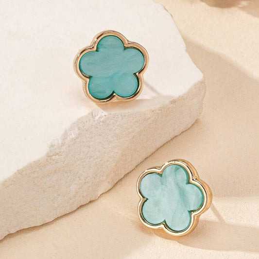A pair of aqua flower earrings with gold-tone borders displayed on a beige surface.