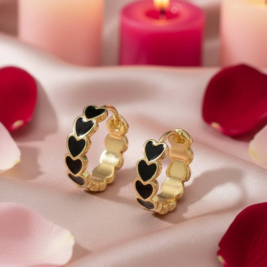 Black Heart Hoop Earrings with black heart details on a soft fabric background with candles and petals.