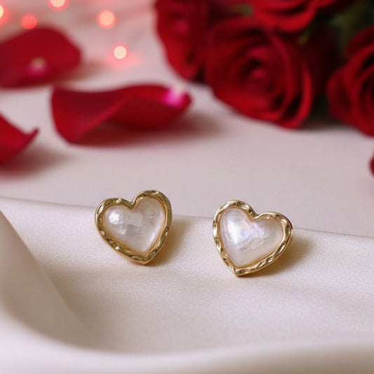 Gold & White Opalescent Heart Earrings with gold frames on a beige fabric background