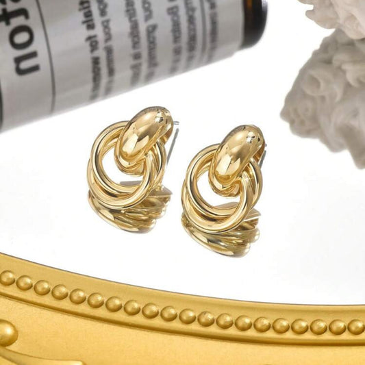 Gold circle knot earrings on a mirror