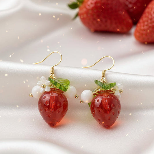 Strawberry Flower Earrings with gold hooks on a white surface with strawberries in the background.