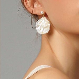 Pearl earring worn by a person against a neutral background