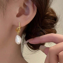Load image into Gallery viewer, Gold knot earring with a pearl drop worn by a person.