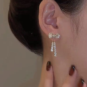 Gold bow-shaped stud earrings adorned with small rhinestones