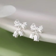 Load image into Gallery viewer, Silver bow-shaped earrings with dangling elements on a white surface.