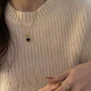 Gold heart necklace with reversible black and white enamel sides