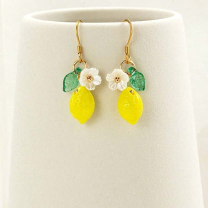 Pair of earrings with lemon and flower designs on a white background