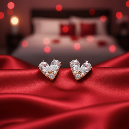 Pearl Heart Zircon Earrings on a red satin surface with a blurred bedroom background.