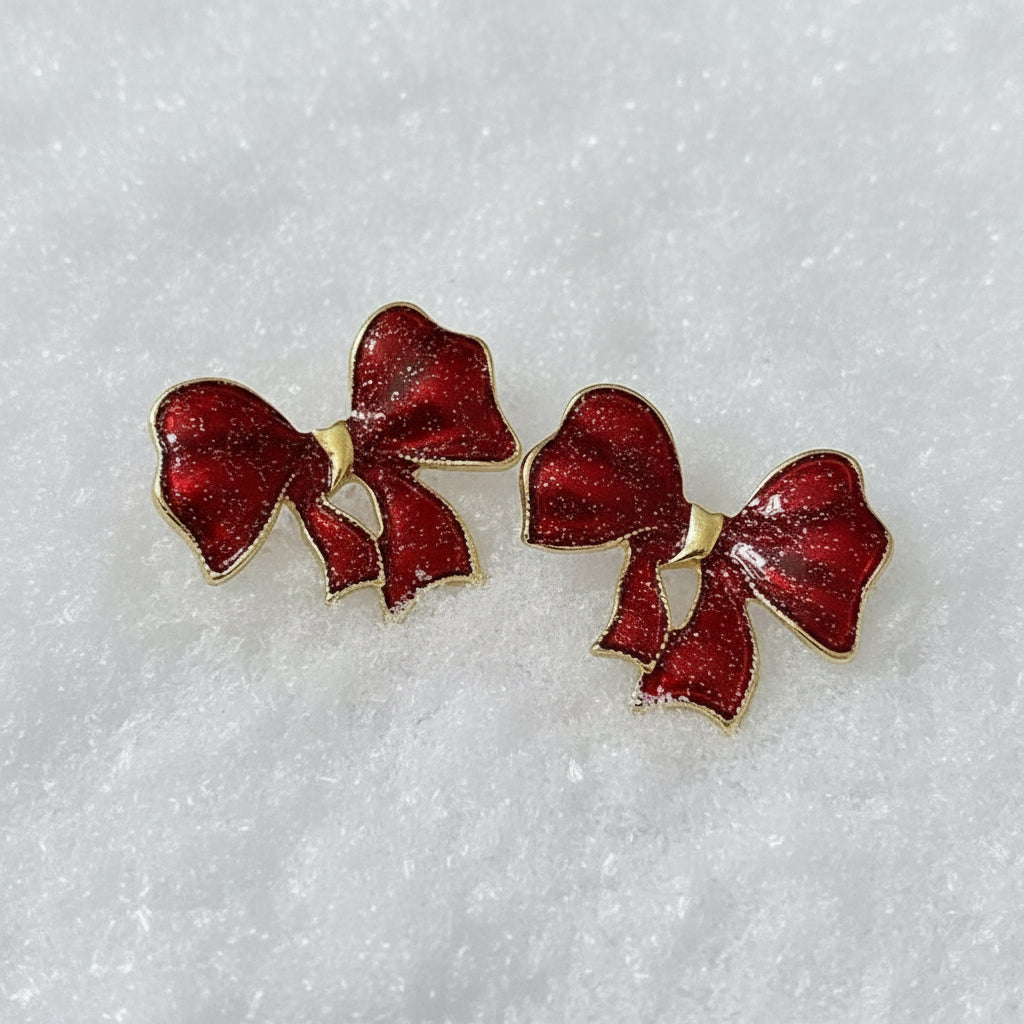Crimson Glitter Bow Earrings on a white satin background