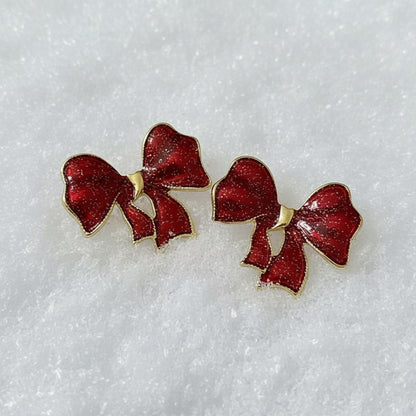 Crimson Glitter Bow Earrings on a white satin background