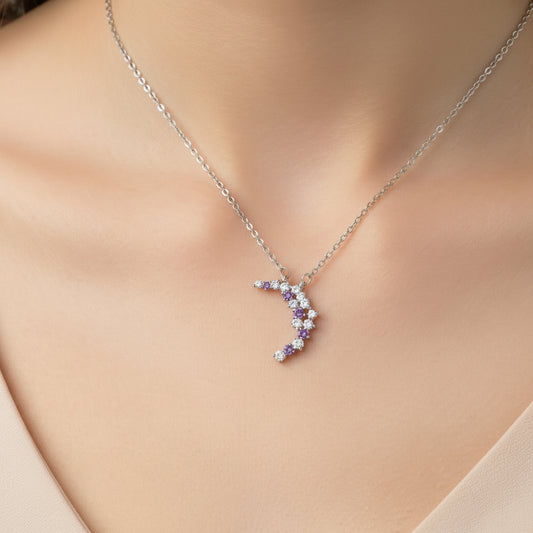 Purple & Silver Crescent Moon Necklace with purple and clear gemstones on a light blue background