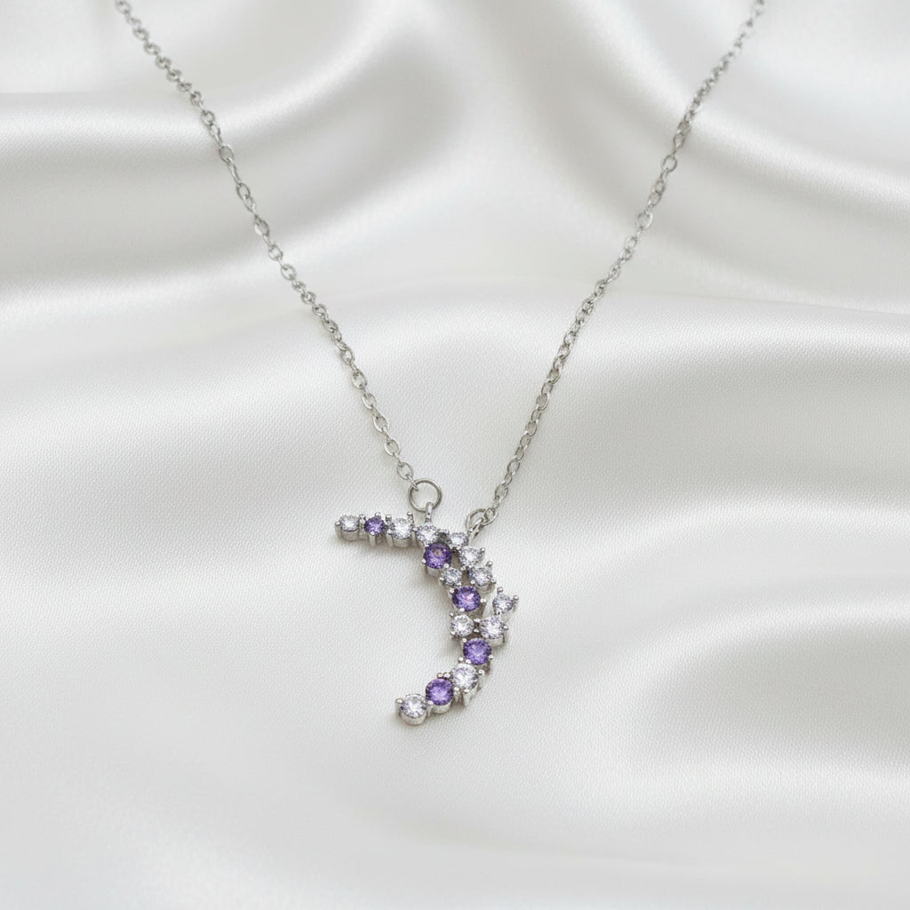 Purple & Silver Crescent Moon Necklace with purple and clear gemstones on a light blue background