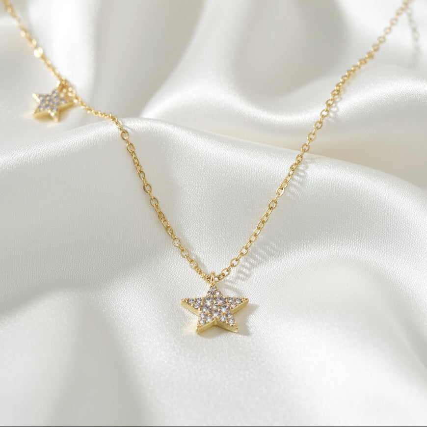 Gold Double Star Necklace on a white satin background