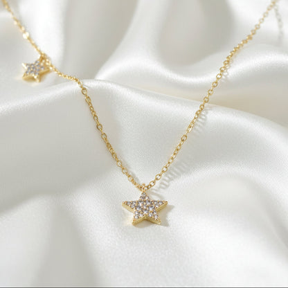 Gold Double Star Necklace on a white satin background