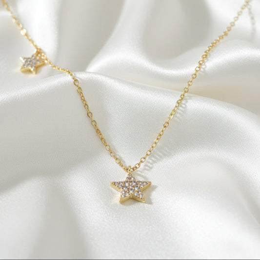 Gold Double Star Necklace on a white satin background
