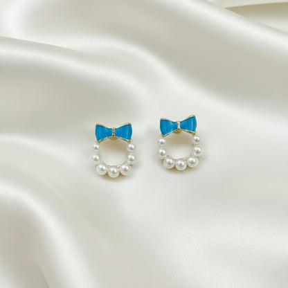 Blue Bow Pearl Wreath Earrings on a satin background
