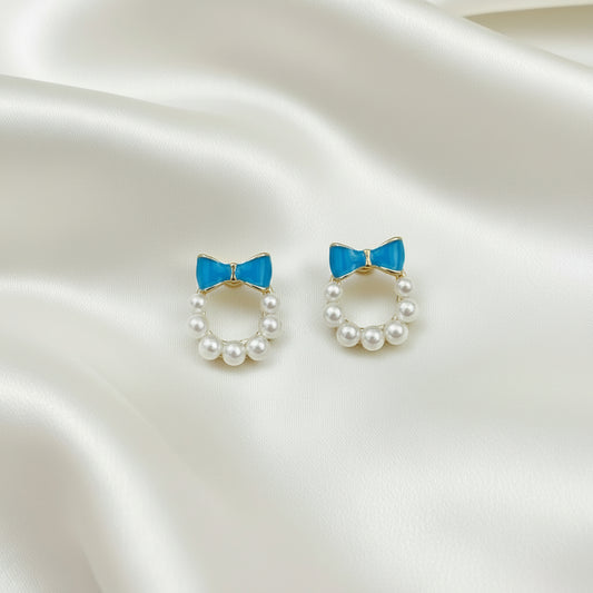 Blue Bow Pearl Wreath Earrings on a satin background