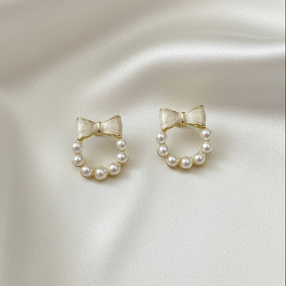 Pair of Ivory Bow Pearl Wreath Earrings on a satin surface