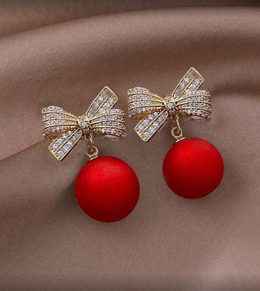 Red Ornament Bow Earrings on fabric background
