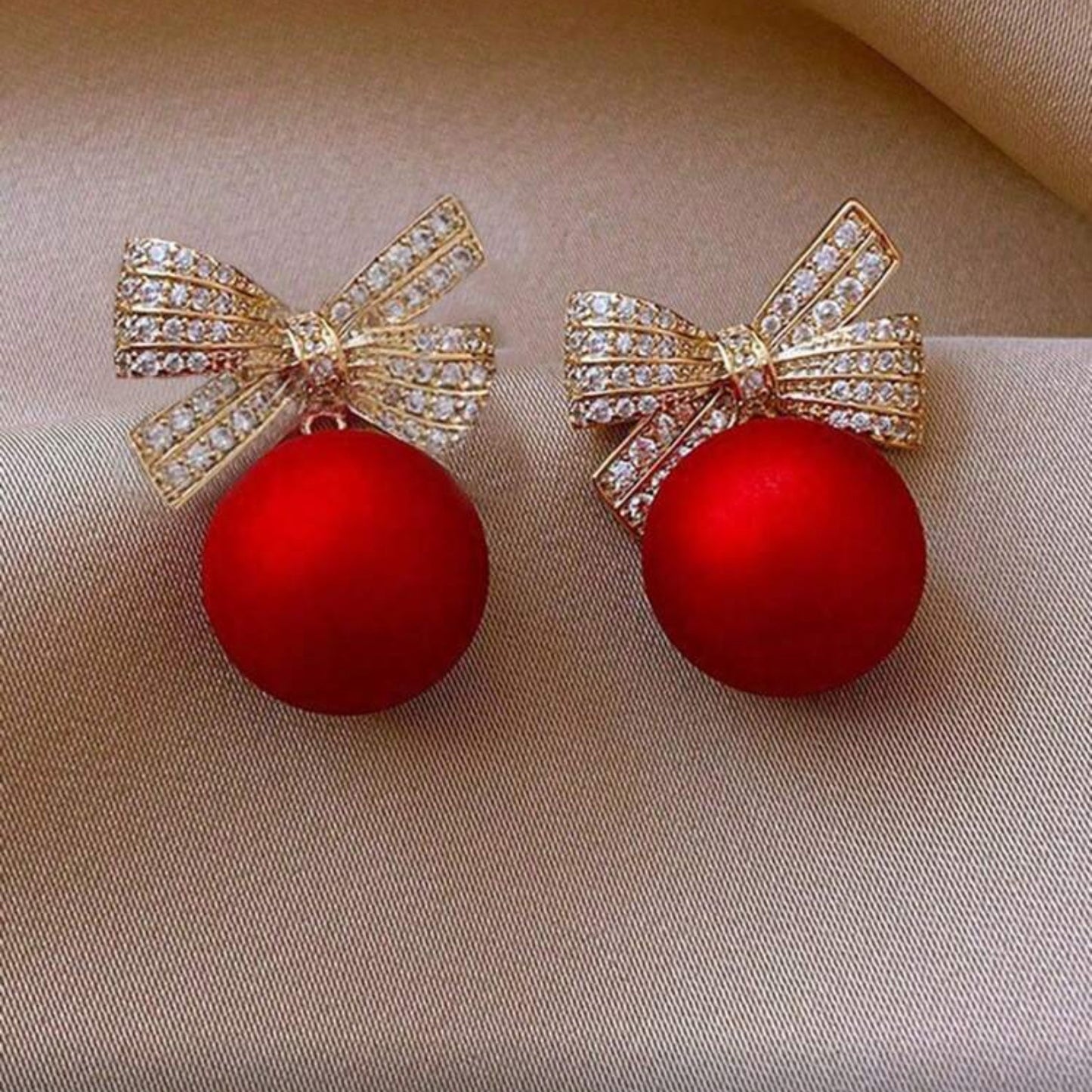 Red Ornament Bow Earrings on fabric background
