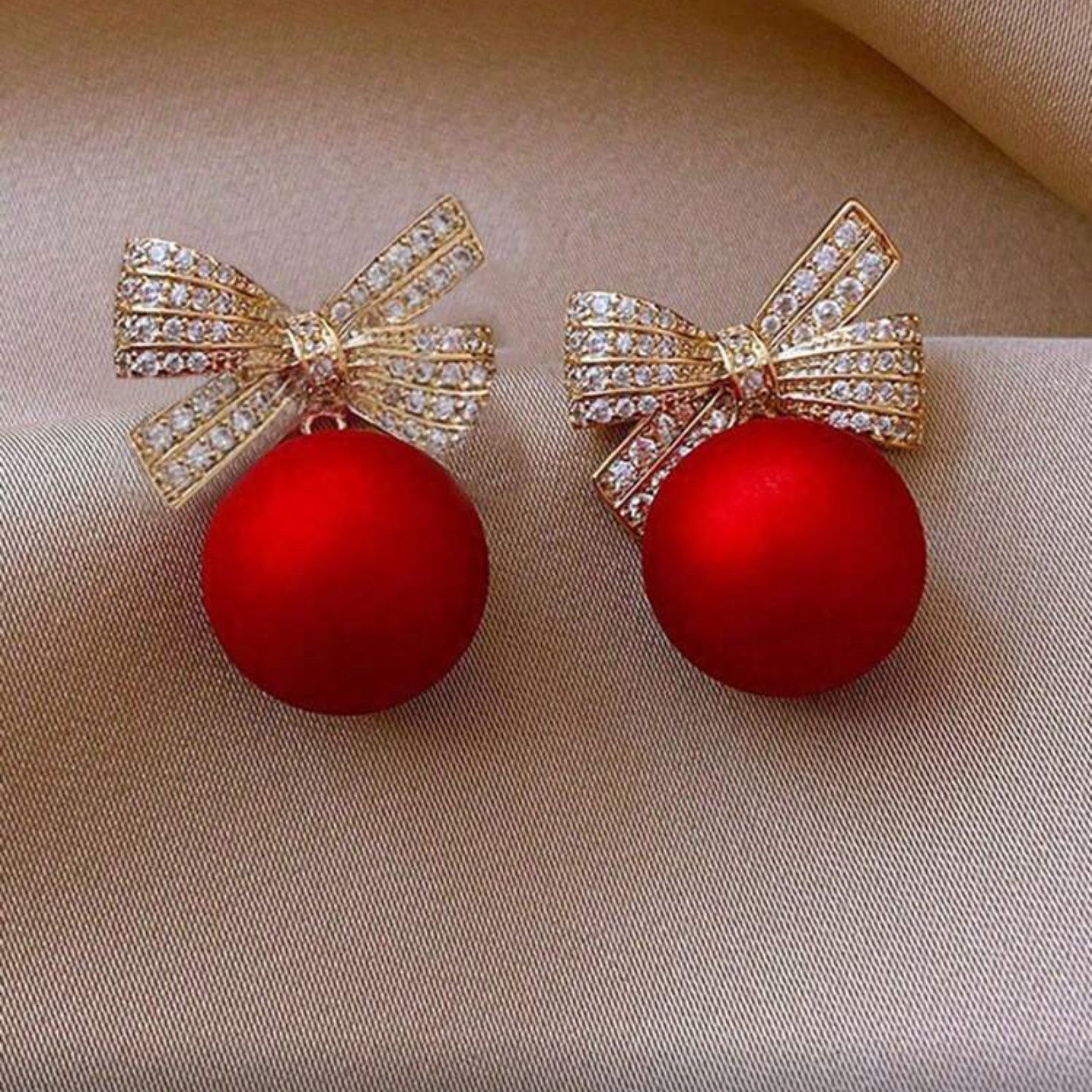 Red Ornament Bow Earrings on fabric background