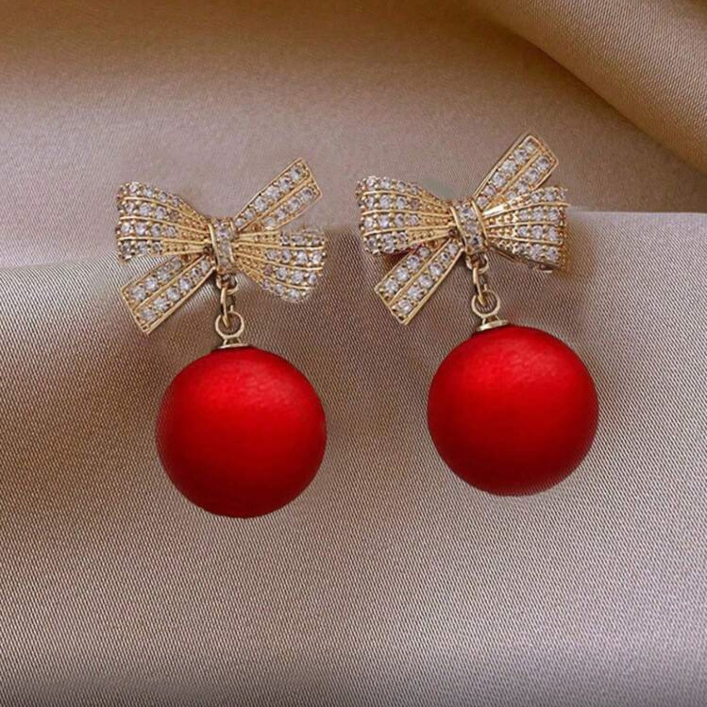 Red Ornament Bow Earrings on fabric background