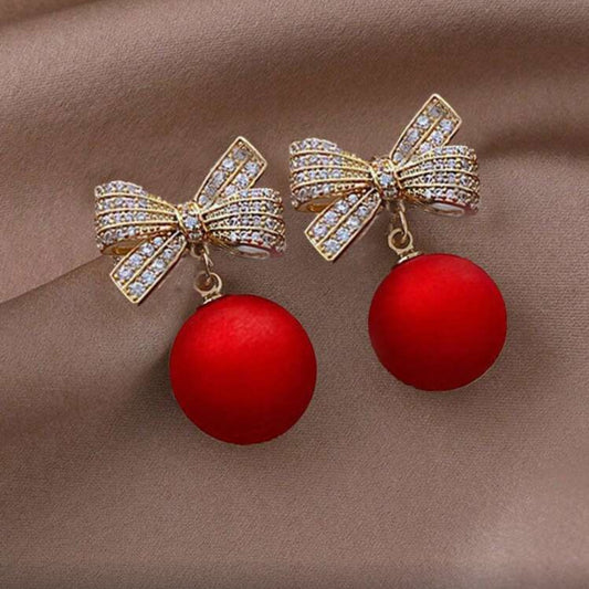 Red Ornament Bow Earrings on fabric background