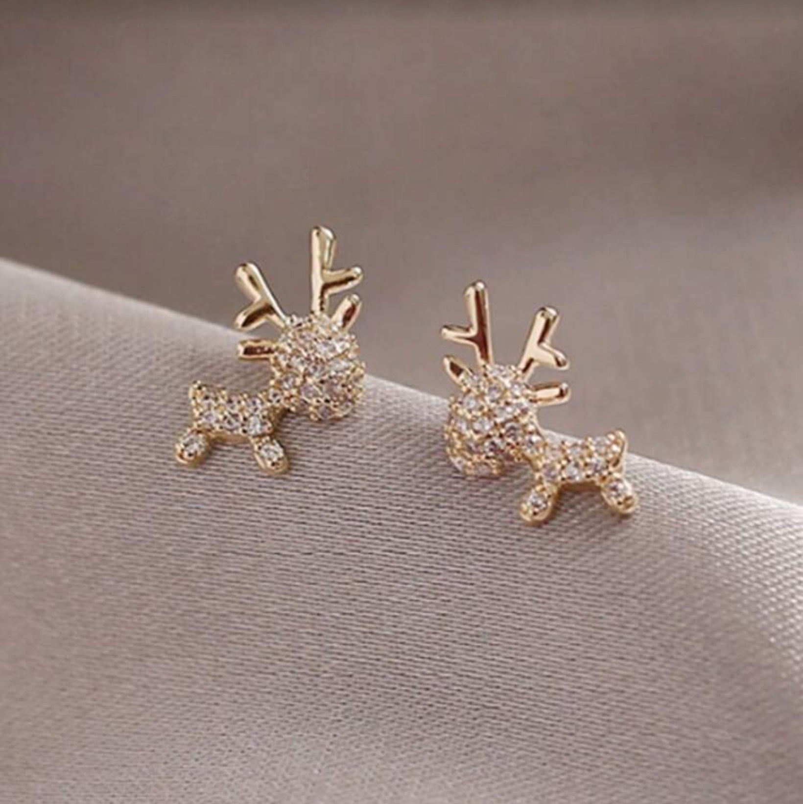 Zircon Deer Earrings on a soft fabric background