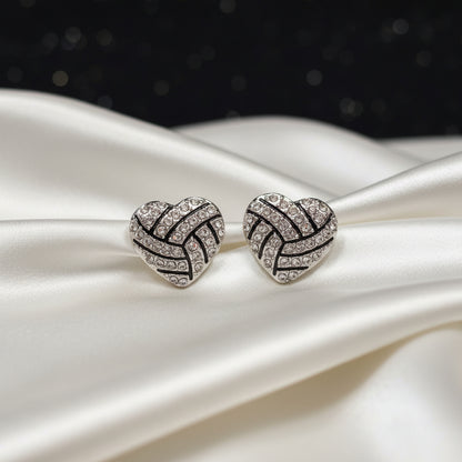 Silver & Black Rhinestone Heart Stud Earrings with zigzag pattern on a round beige stone surface.