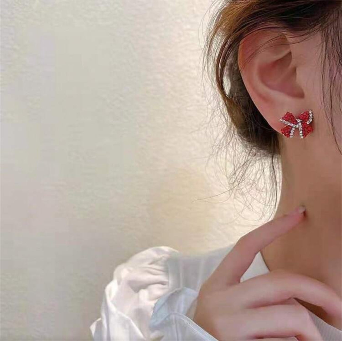 Red Bow Earrings worn by a person with a blurred background
