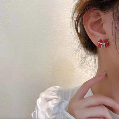 Red Bow Earrings worn by a person with a blurred background