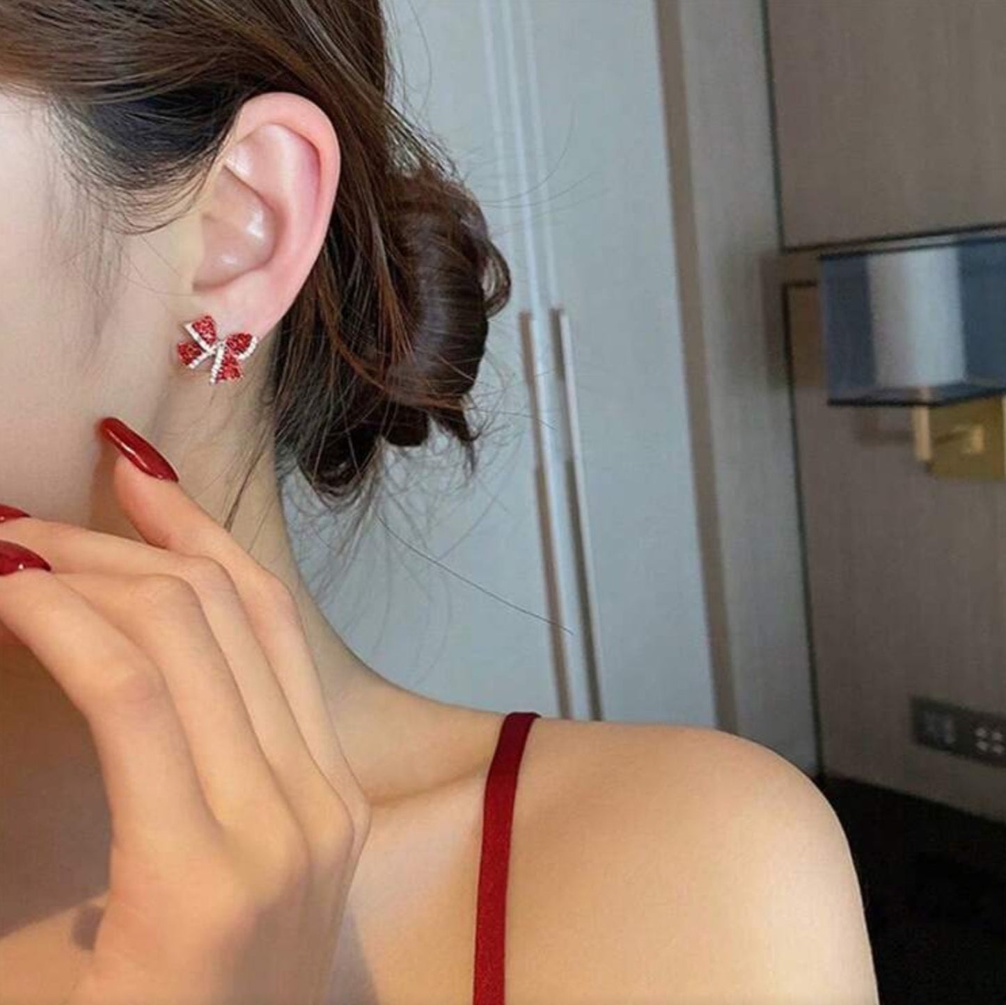 Close-up of a person wearing Red Bow Earrings with a neutral background