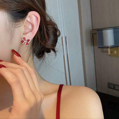 Close-up of a person wearing Red Bow Earrings with a neutral background