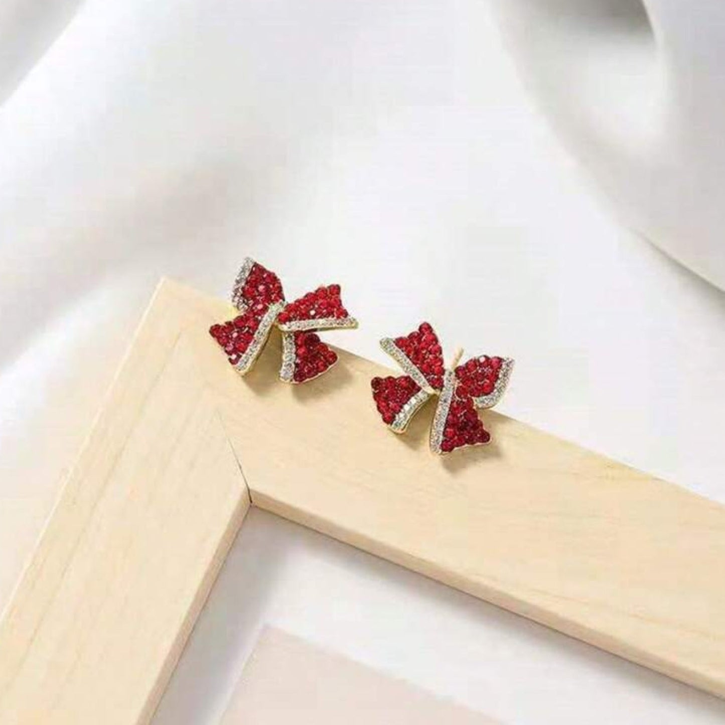 Red Bow Earrings with red gemstones on a white background