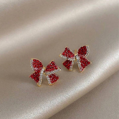 Red Bow Earrings with red gemstones on a beige fabric background