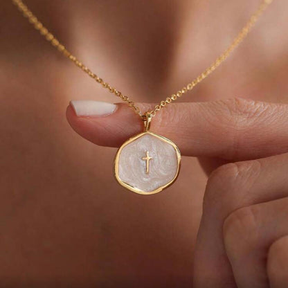 Walk in Faith Enamel Cross Necklace featuring a cross held by a hand against a blurred background