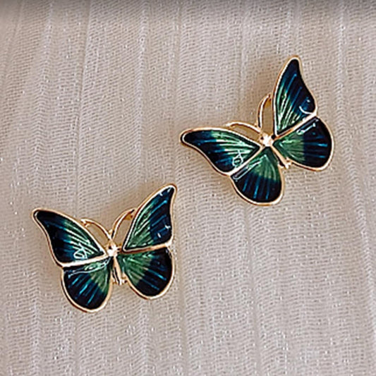 Blue & Green Butterfly Earrings on a beige fabric background