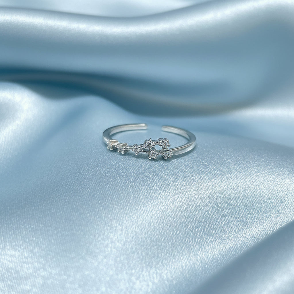 Silver Cancer Zodiac Ring on a light blue satin background