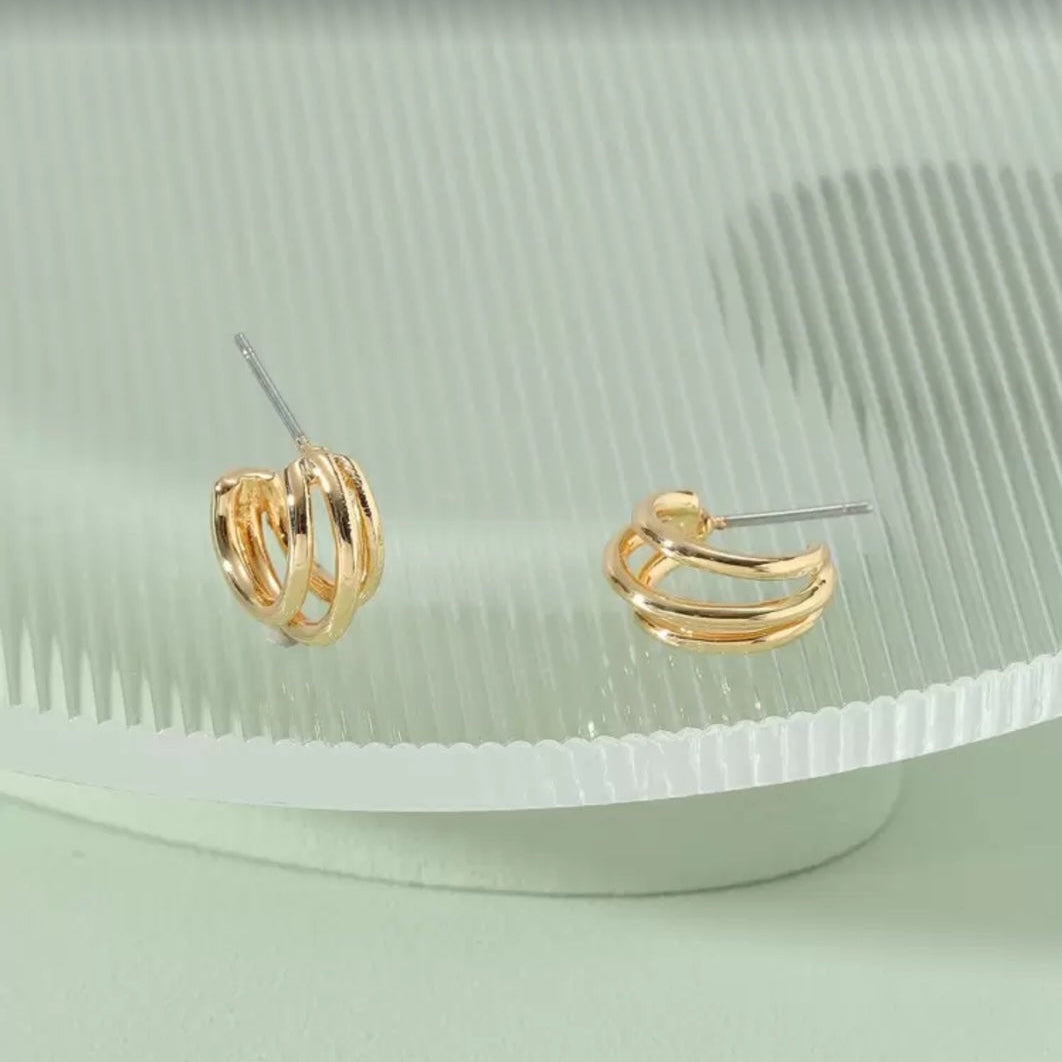 Triple Band Gold Hoop Earrings on a light green background